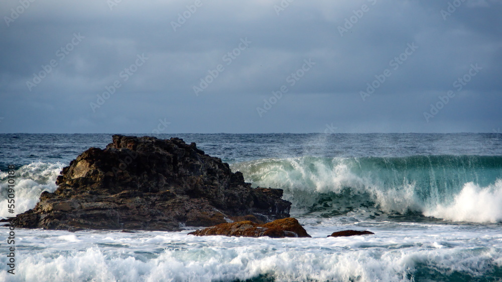 Waves breaking on the beach, with a rock just offshore, in Zipolite, Mexico