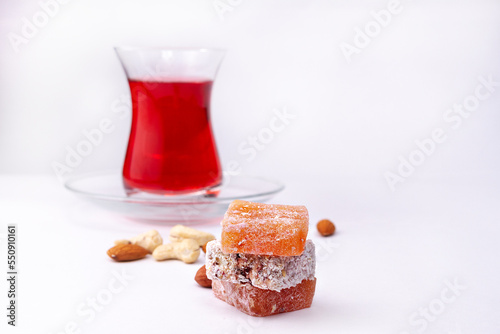 Oriental sweetness rahat lakoum on white background with glass of tea and nuts photo
