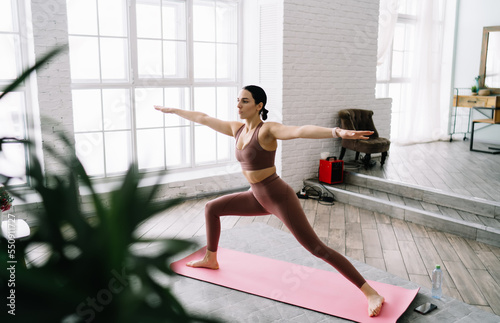 Slim woman practicing yoga pose in living room
