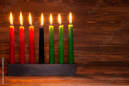 Kwanzaa festival concept with seven candles red, black and green in candlestick on wooden background, copy space photo