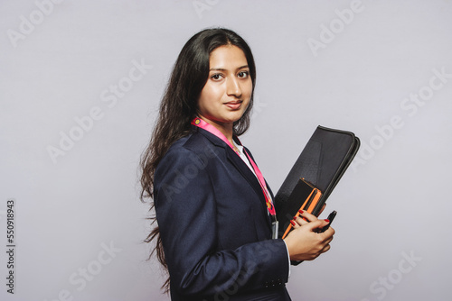 beautiful indian millennial girl holding book in grey background photo