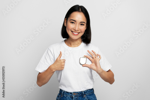 Pretty asian woman holding Implantable cardioverter defibrillator (ICDs) and showing cool gesture photo
