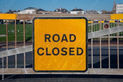 Orange road closed sign on a metal gate.