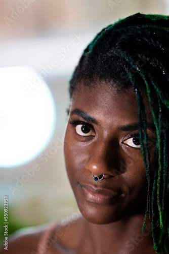 Black woman with green dreadlocks staring and smiling