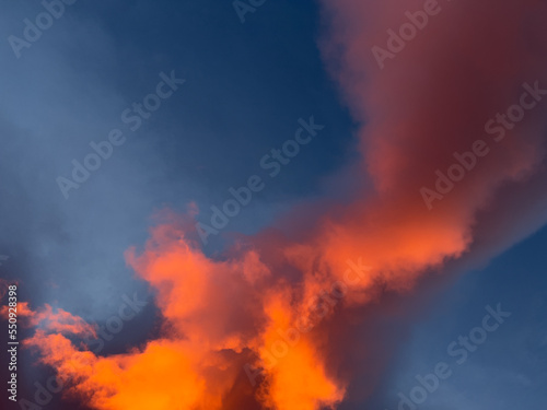 Sunrise overhead looks like bright orange fire in the dark blue sky. Clouds are large and swirling.