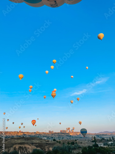 Hot air balloon flying over rocky landscapes in Cappadocia with beautiful sky on background