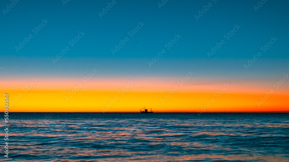 lonely boat sailing in horizon during sunrise lonely boat sailing in horizon during sunrise