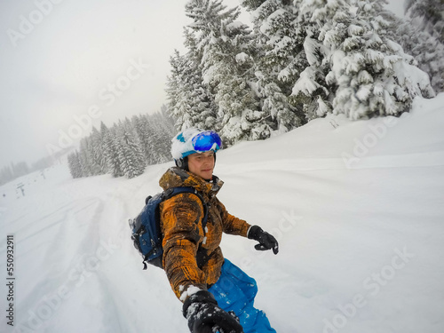 Snowboarder in bright clothes quickly descend from a snowy mountain in cloudy weather. Ski resort. Freeride