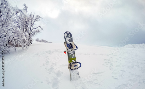 The snowboard stands in the snow high up in the snowy mountains. Sunny weather. ski resort