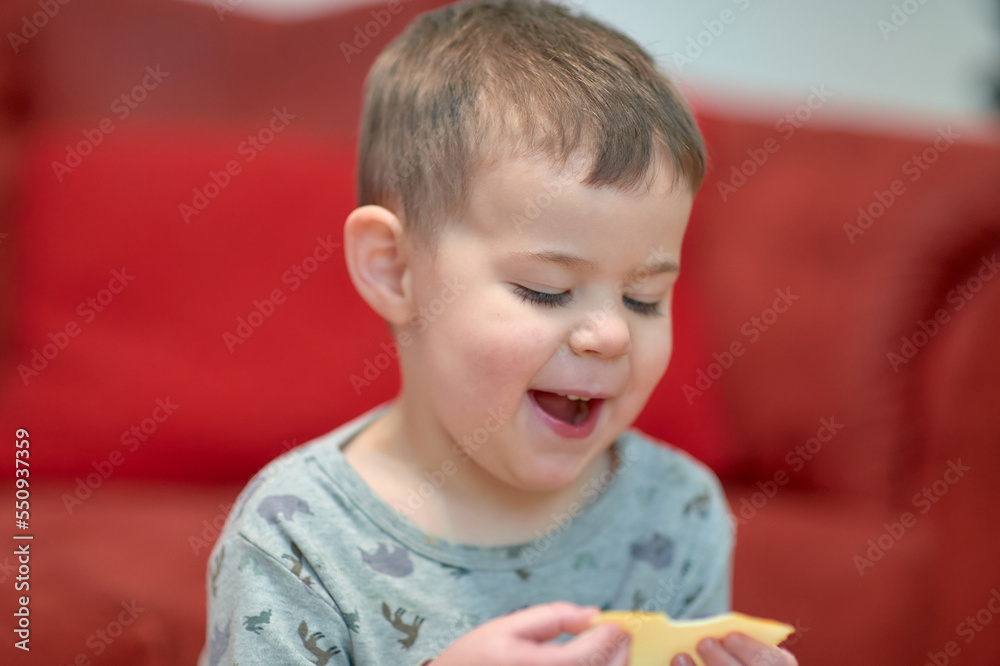 expressive young boy eating cheese at home while watching tv next to the couch expressive young boy eating cheese at home while watching tv next to the couch
