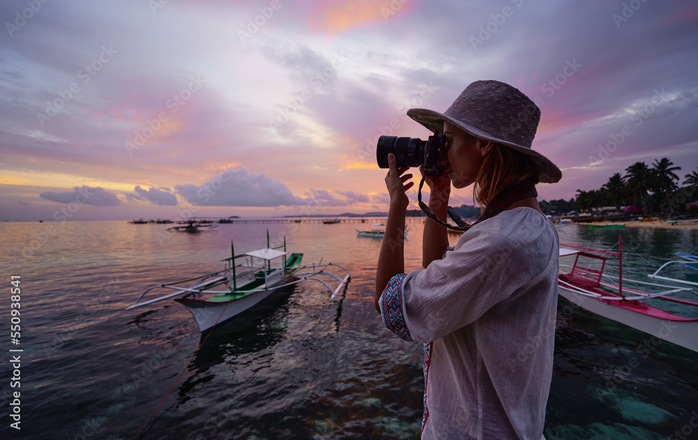Photography and travel. Young woman in hat holding camera  with beautiful tropical sea view. - obrazy, fototapety, plakaty 