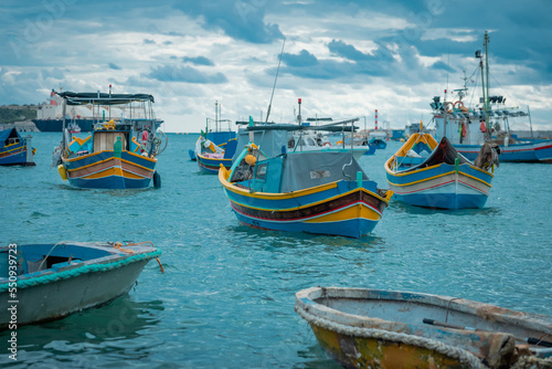 Luzzu, typical fishing boats of Malta moored in the marina of Marsaxlokk on an autumn day. Many ships in the bay, nice blue feeling