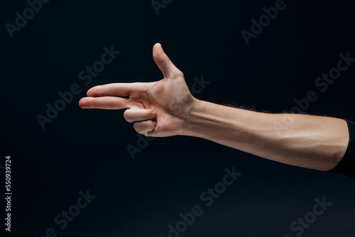 Man's hand showing gun gesture isolated over dark background.
