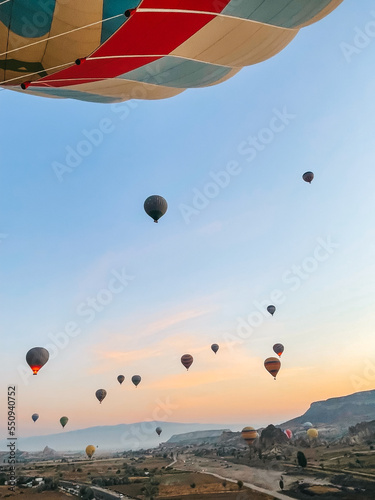 Hot air balloon flying over rocky landscapes in Cappadocia with beautiful sky on background