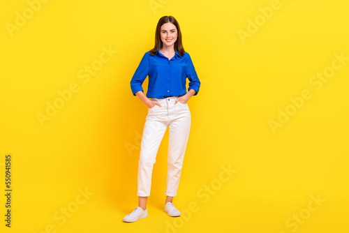 Full length photo of adorable charming girl dressed blue shirt standing arms pockets isolated yellow color background