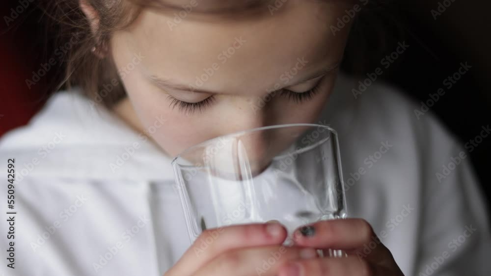 Water balance and children health care. Little girl drinks fresh transparent pure filtered mineral water at home. Thirsty dehydrated teenager holds glass hydrating thirst in the morning to be healthy. Water balance and children health care. Little girl drinks fresh transparent pure filtered mineral water at home. Thirsty dehydrated teenager holds glass hydrating thirst in the morning to be healthy.