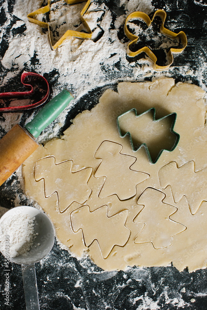 Cutting Christmas tree shapes into freshly rolled sugar cookie dough Cutting Christmas tree shapes into freshly rolled sugar cookie dough