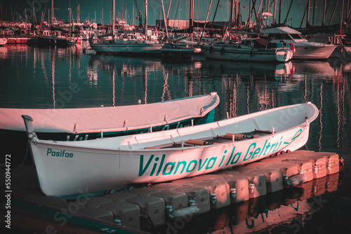 Rowing boats moored in the port of vilanova i la geltrú during sunset, name of the town written on them photo