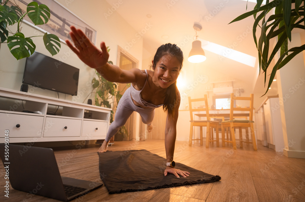Beautiful Asian woman training fitness at home and using laptop Beautiful Asian woman training fitness at home and using laptop