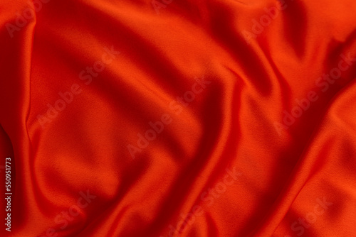 Texture of red fabric close-up. Textile as abstract background. Silk or satin material. Plain bright cloth