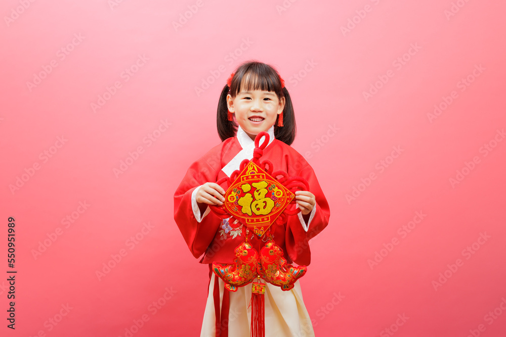 Chinese girl with traditional dressing up hold a Fu means 'lucky' greeting sign against pink background Chinese girl with traditional dressing up hold a Fu means 'lucky' greeting sign against pink background