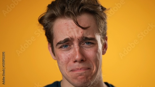 Closeup portrait of sad, unhappy, angry, upset, frustrated, young man 20s isolated on yellow color background in studio. Sincere emotions lifestyle concept