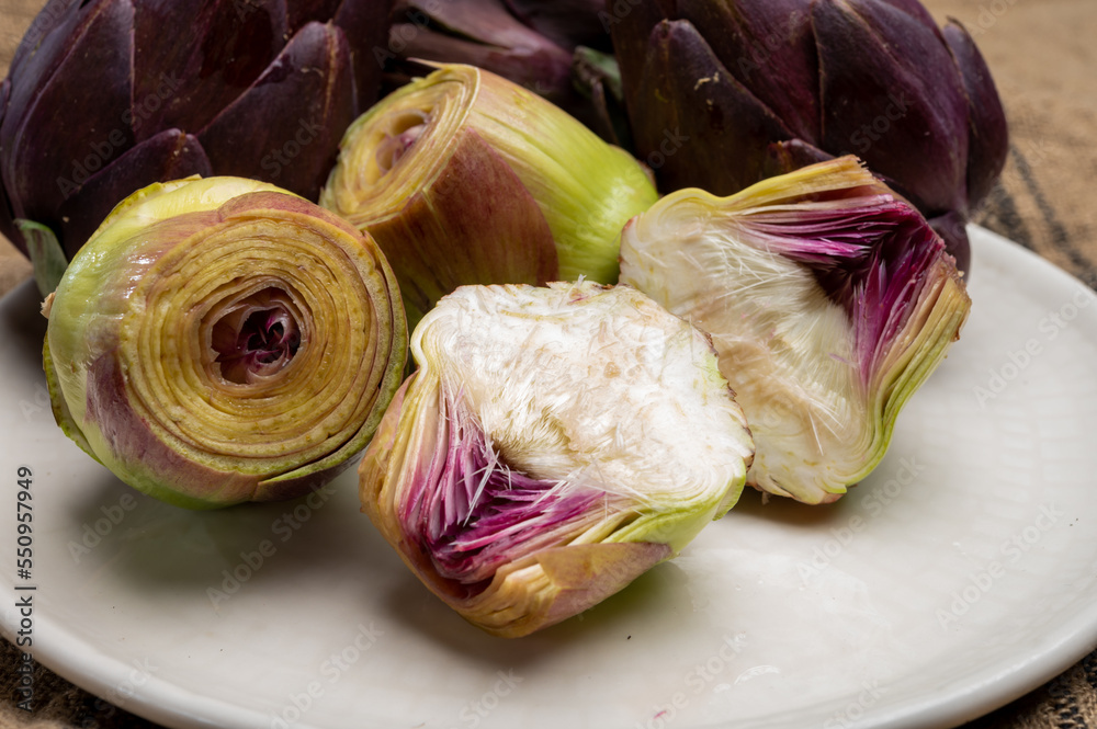 Fototapeta premium Heads of raw fresh purple romanesco artichoke vegetable heads and pilled hearts