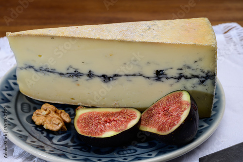 French semi-soft cow milk cheese morbier from Franche-Comte region with thin black layer and strong aroma close up