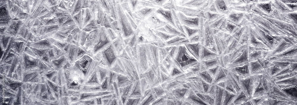 The texture of the ice surface. Winter background, festive background in the form of ice crystals, in natural deep blue color. The texture of the ice surface. Winter background, festive background in the form of ice crystals, in natural deep blue color.