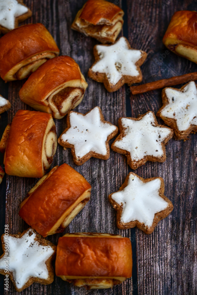 Freshly baked cinnamon buns with spices and cocoa filling on parchment paper. Top view. Sweet Homemade Pastry christmas baking. Close-up. Kanelbule - swedish dessert.and star shaped Christmas cookies Freshly baked cinnamon buns with spices and cocoa filling on parchment paper. Top view. Sweet Homemade Pastry christmas baking. Close-up. Kanelbule - swedish dessert.and star shaped Christmas cookies