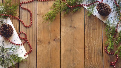 Christmas Flatlay of Pine Cones, Red Ornaments, Beads, Sheet Music, and Evergreen Boughs on a Wooden Background | Rustic Christmas Decorations