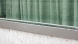 Cortina verde en ventana con marco metálico