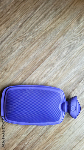 purple rubber hot water bottle on wooden background