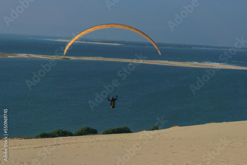 Single paraglider flying in the windy air over the dune of Pilat on a sunny day, Arcachon, Nouvelle-Aquitaine, France