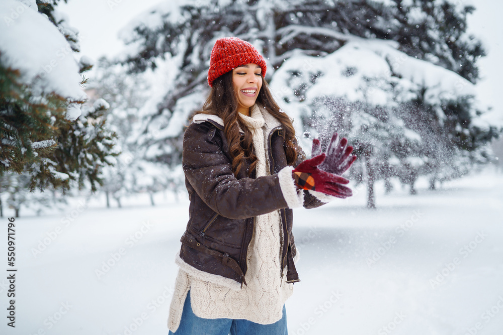 Young woman laughs and throws snow in a winter snowy park. Holidays, rest, travel concept. Young woman laughs and throws snow in a winter snowy park. Holidays, rest, travel concept.