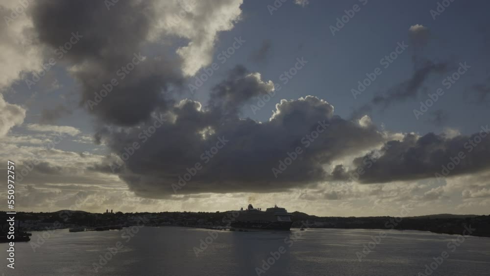 Zoom in to distant cruise ship under dark clouds at sunset / St. Johns, Antigua, Antigua and Barbuda Zoom in to distant cruise ship under dark clouds at sunset / St. Johns, Antigua, Antigua and Barbuda
