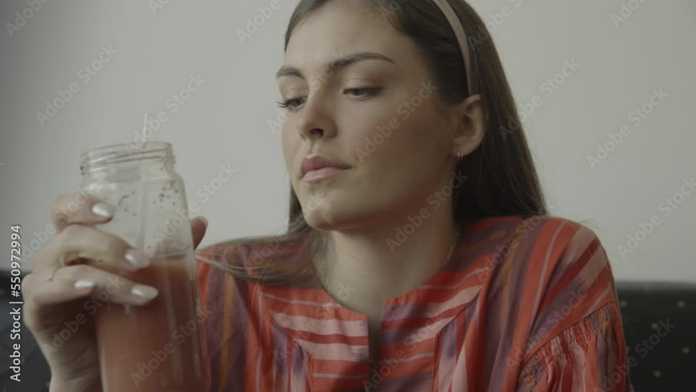 Close up of pensive woman drinking juice from jar with straw / Provo, Utah, Unites States Close up of pensive woman drinking juice from jar with straw / Provo, Utah, Unites States