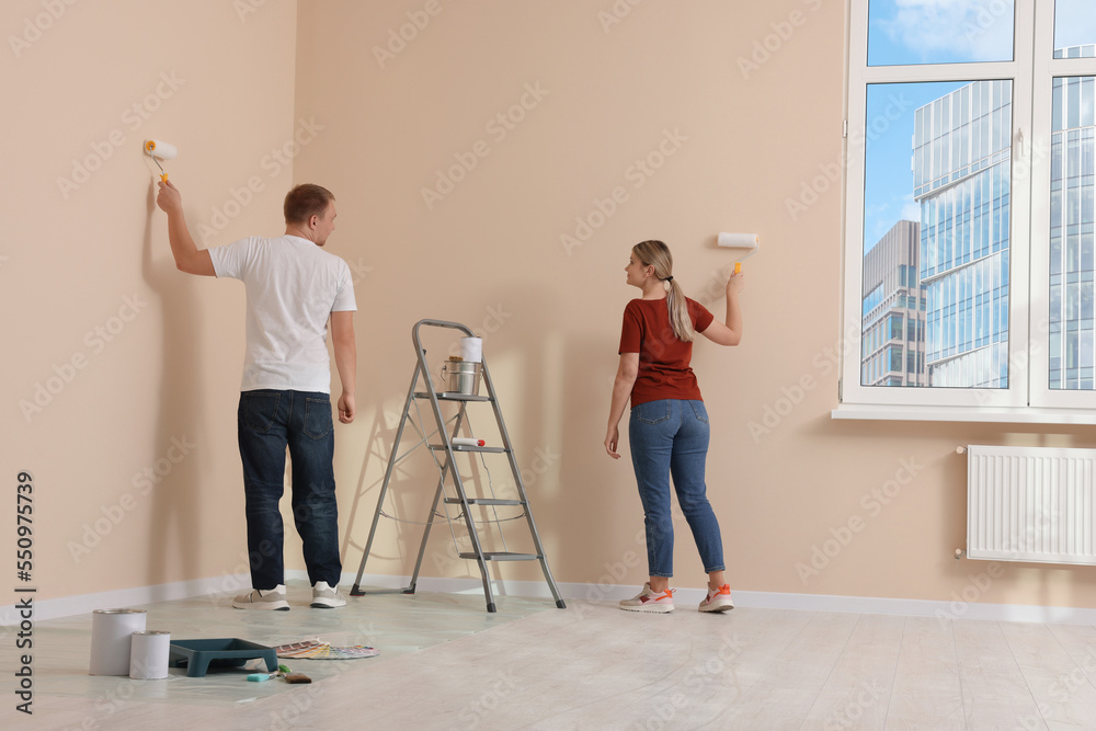 Couple painting wall in apartment during repair