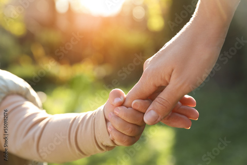 Daughter holding mother's hand outdoors, closeup view © New Africa