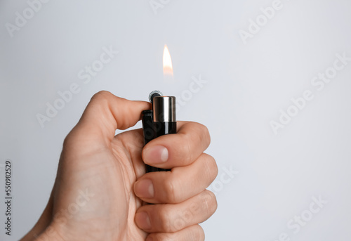 Woman holding black lighter on white background, closeup