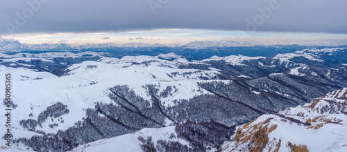 Panoramic aerial view of Caucasus Mountain Range from Gum Bashi pass on cloudy winter day. Karachay-Cherkessia, Russia. © Kirill