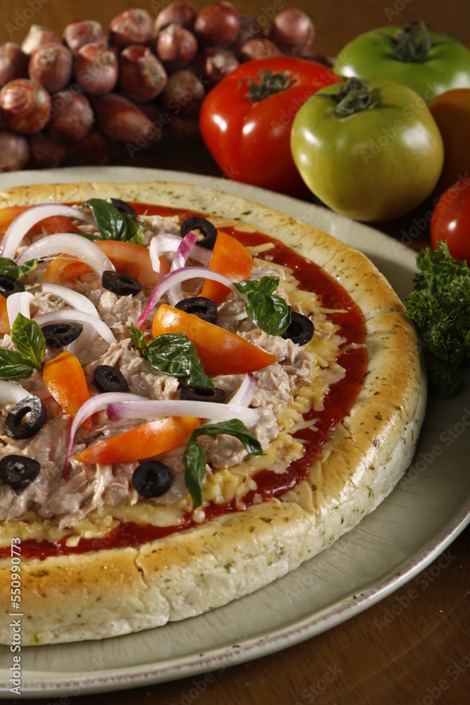 Fresh whole and unsliced tuna pizza with ingredients at the side Fresh whole and unsliced tuna pizza with ingredients at the side