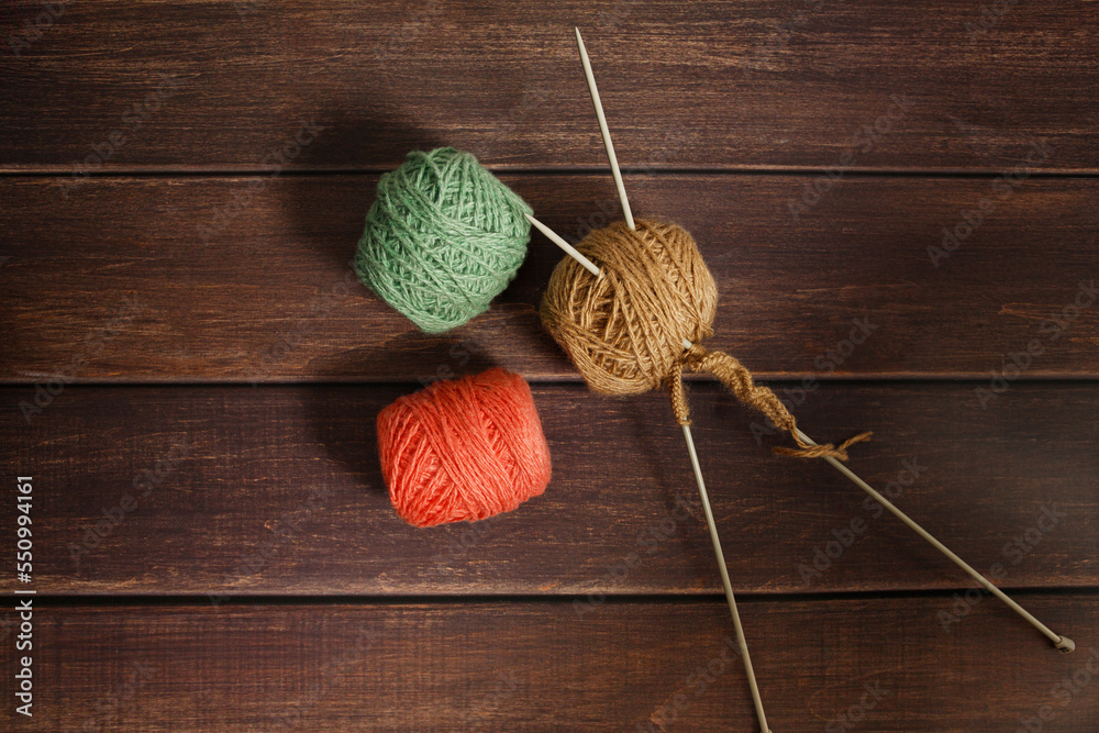 Knitting wool and knitting needles on dark wooden background. Top view handmade background. Copy space banner