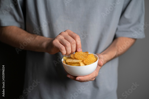 hand holding potato chips in white bowl