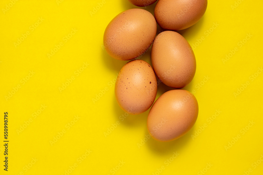 Brown chicken eggs on yellow background. Fresh chicken eggs background. Top view with copy space