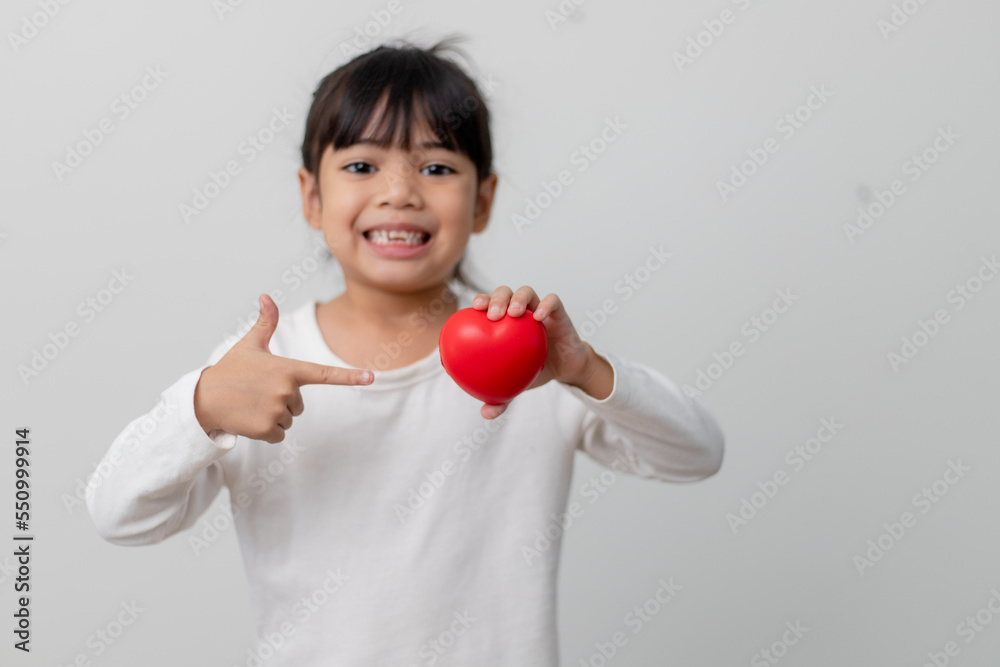 Portrait of Asian little girl child holding red heart sign on white background Portrait of Asian little girl child holding red heart sign on white background