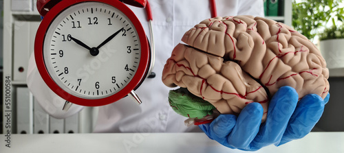 Doctors in gloves hold red alarm clock and brain mockup photo