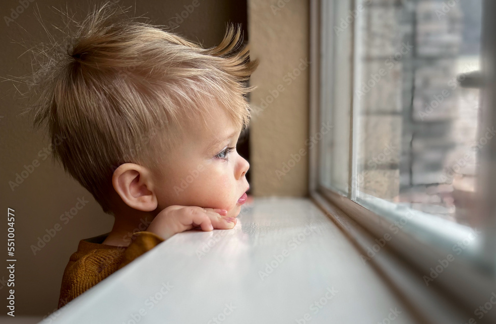 Cute little toddler looking at the window at home, close up portrait Cute little toddler looking at the window at home, close up portrait