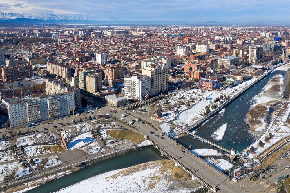 Aerial view of Vladikavkaz and a bridge across Terek river on sunny winter day. North Ossetia, Russia.