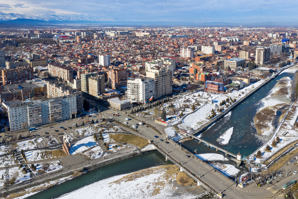 Aerial view of Vladikavkaz and a bridge across Terek river on sunny winter day. North Ossetia, Russia. Aerial view of Vladikavkaz and a bridge across Terek river on sunny winter day. North Ossetia, Russia.